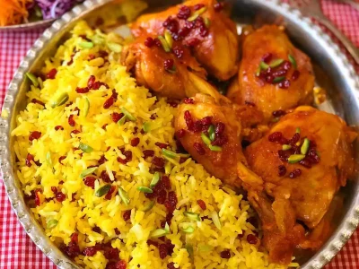 زرشک پلو با مرغ: مجلسی، خوشمزه و پرطرفدار! طعم ترش و شیرین زرشک و مرغی که به بهترین شکل پخته شده، ترکیبی بی‌نظیر برای یک غذای خاطره‌انگیز! زرشک پلو با مرغ یکی از غذاهای محبوب ایرانی است که به دلیل طعم بی‌نظیر و ظاهر مجلسی‌اش، در بسیاری از مهمانی‌ها و دورهمی‌ها سرو می‌شود. این غذا به دو صورت با مرغ ریش ریش شده یا مرغ تکه‌ای پخته می‌شود و شما می‌توانید مطابق سلیقه خودتان آن را تهیه کنید. در این مطلب، طرز تهیه زرشک پلو با مرغ مجلسی را به صورت آسان و تصویری به شما آموزش می‌دهیم تا بتوانید به راحتی این غذای خوشمزه را در منزل تهیه کنید و از آن لذت ببرید. مواد لازم (برای 4 نفر): مرغ: 500 گرم ران مرغ 1 عدد پیاز متوسط 2 حبه سیر 1 قاشق غذاخوری نمک 1/2 قاشق چای‌خوری فلفل سیاه 1/2 قاشق چای‌خوری زردچوبه 2 قاشق غذاخوری روغن مایع 2 قاشق غذاخوری رب گوجه‌فرنگی 2 لیوان آب برنج: 2 پیمانه برنج ایرانی 3 پیمانه آب 1 قاشق غذاخوری نمک 2 قاشق غذاخوری روغن مایع زرشک: 1/2 پیمانه زرشک 1/4 پیمانه آب 1 قاشق غذاخوری شکر 1 قاشق غذاخوری گلاب زعفران: به مقدار لازم مقداری آب جوش تخمه: به مقدار دلخواه (تخمه آفتابگردان، تخمه کدو، خلال بادام و ...) مراحل پخت: 1. پخت مرغ: ران مرغ را بشویید و به تکه‌های دلخواه خرد کنید. (تصویر 1) پیاز را نگینی خرد کنید و در قابلمه‌ای با روغن مایع تفت دهید تا شفاف شود. (تصویر 2) سیر را نیز ریز خرد کرده و به پیازها اضافه کنید و به تفت دادن ادامه دهید تا عطر سیر بلند شود. (تصویر 3) تکه‌های مرغ را به پیازها اضافه کنید و به همراه نمک، فلفل سیاه و زردچوبه تفت دهید تا مرغ به طور کامل سرخ شود. (تصویر 4) رب گوجه‌فرنگی را اضافه کنید و به تفت دادن ادامه دهید تا رنگ رب باز شود. (تصویر 5) 2 لیوان آب به مرغ اضافه کنید و حرارت را کم کنید. در قابلمه را ببندید و اجازه دهید مرغ به مدت 45 دقیقه تا 1 ساعت بپزد و جِرمی که از مرغ جدا می‌شود را با قاشق جمع کنید. (تصویر 6) 2. پخت زرشک: زرشک را پاک کنید و بشویید. (تصویر 7) در قابلمه‌ای آب، شکر و گلاب را با هم مخلوط کنید و روی حرارت قرار دهید تا بجوشد. زرشک را به شربت اضافه کنید و به مدت 5 تا 10 دقیقه بجوشانید تا زرشک پخته و رنگ آن قرمز شود. (تصویر 8) حرارت را خاموش کنید و اجازه دهید زرشک خنک شود. 3. دم کردن برنج: برنج را بشویید و به مدت 30 دقیقه در آب و نمک خیس کنید. در قابلمه‌ای آب به جوش برسانید و برنج را به آن اضافه کنید. بعد از اینکه برنج به جوش آمد، حرارت را کم کنید، در قابلمه را ببندید و اجازه دهید برنج به مدت 20 تا 25 دقیقه دم بکشد. 4. زعفران دم کردن: مقداری زعفران را در هاون یا آسیاب پودر کنید. به زعفران پودر شده، مقداری آب جوش اضافه کنید و هم بزنید تا زعفران دم بکشد. 5. سرو زرشک پلو با مرغ: برنج را در ظرف مورد نظر بریزید و با زعفران دم کرده تزیین کنید. مرغ پخته شده را روی برنج قرار دهید. زرشک پخته شده را روی مرغ و برنج بریزید. تخمه دلخواهتان را روی زرشک