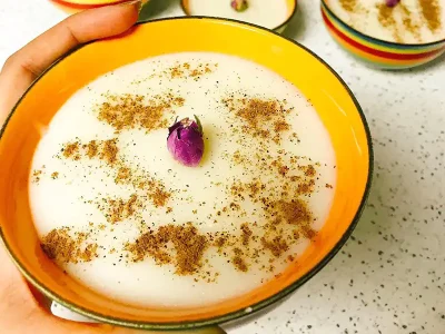 طرز تهیه فرنی خوشمزه و خانگی فرنی یکی از دسرهای سنتی و محبوب ایرانی است که با طعم شیرین و بافت نرمش، برای همه سنین مناسب است. برای تهیه فرنی، می‌توانید از آرد برنج، نشاسته ذرت یا ترکیبی از هر دو استفاده کنید. مواد لازم: آرد برنج یا نشاسته ذرت: نصف پیمانه شیر: 4 پیمانه شکر: یک سوم پیمانه گلاب: 2 قاشق غذاخوری کره: 20 گرم دارچین: به مقدار دلخواه (برای تزیین) طرز تهیه: آماده سازی آرد: آرد برنج یا نشاسته ذرت را با کمی شیر سرد مخلوط کنید تا گلوله نشود. پختن فرنی: شیر باقی مانده را در یک قابلمه روی حرارت ملایم قرار دهید. پس از گرم شدن شیر، مخلوط آرد و شیر سرد را به آرامی به شیر اضافه کنید و مرتب هم بزنید تا آرد گلوله نشود. اضافه کردن شکر و گلاب: بعد از غلیظ شدن فرنی، شکر و گلاب را اضافه کرده و هم بزنید تا یکدست شود. پخت نهایی: فرنی را به مدت 5-10 دقیقه دیگر با حرارت ملایم هم بزنید تا کاملا بپزد و غلیظ شود. سرو کردن: فرنی آماده را در ظرف مورد نظر ریخته و با کره و دارچین تزیین کنید.